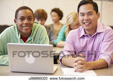 Stock Image - High School Student With Teacher In Class Using Laptop. Fotosearch
