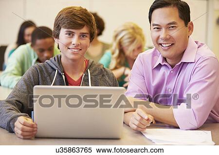 Stock Photography - High School Student With Teacher In Class Using Laptop. Fotosearch