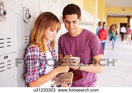 Stock Image - High School Students By Lockers Looking At Mobile Phone. Fotosearch