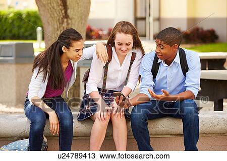 Stock Image - High School Students Using Mobile Phone On School Campus . Fotosearch