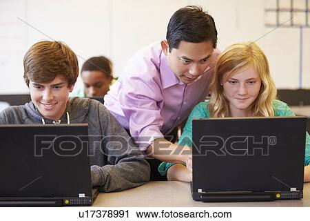 Stock Image - High School Students With Teacher In Class Using Laptops. Fotosearch