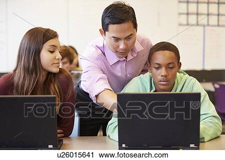 Stock Image - High School Students With Teacher In Class Using Laptops. Fotosearch
