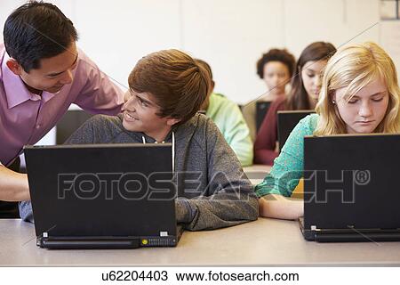 Stock Image - High School Students With Teacher In Class Using Laptops. Fotosearch
