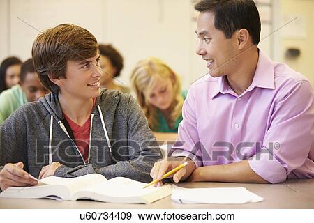 Stock Photo - High School Teacher Helping Student With Written Work. Fotosearch