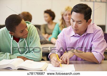 High School Teacher Helping Student With Written Work View Large Photo Image Stock Photo - High School Teacher Helping Student With Written Work. Fotosearch