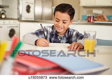 Stock Image - Hispanic Boy Doing Homework At Table. Fotosearch