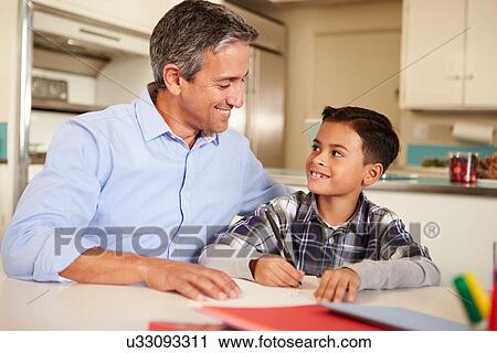 Stock Image - Hispanic Father Helping Son With Homework At Table. Fotosearch