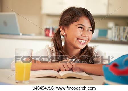 Stock Photograph - Hispanic Girl With Reading Homework At Table. Fotosearch