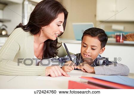 Stock Image - Hispanic Mother Helping Son With Homework At Table. Fotosearch