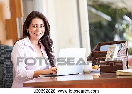 Hispanic Woman Using Laptop On Desk At Home View Large Photo Image Stock Photo - Hispanic Woman Using Laptop On Desk At Home. Fotosearch
