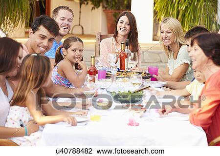 Stock Image - Large Family Group Enjoying Meal On Terrace Together. Fotosearch