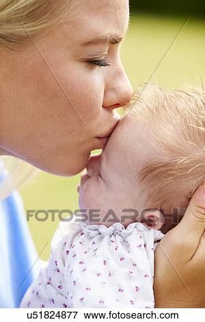 Stock Photo - Loving Mother Kissing Baby Daughter In Garden. Fotosearch