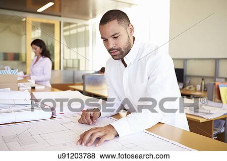 Stock Photo - Male Architect Studying Plans In Office. Fotosearch