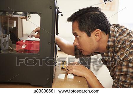 Stock Image - Male Architect Using 3D Printer In Office. Fotosearch