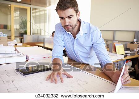 Stock Image - Male Architect With Digital Tablet Studying Plans In Office. Fotosearch