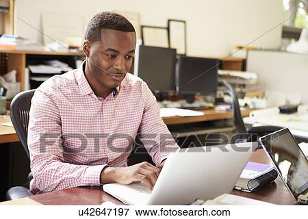Stock Photo - Male Architect Working At Desk On Laptop. Fotosearch