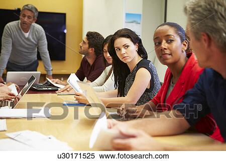 Stock Photography - Male Boss Addressing Meeting Around Boardroom Table. Fotosearch