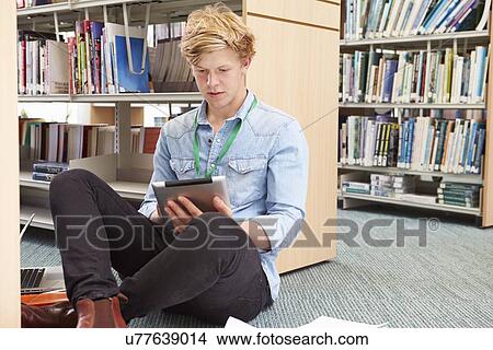 Picture - Male College Student Studying In Library With Digital Tablet. Fotosearch