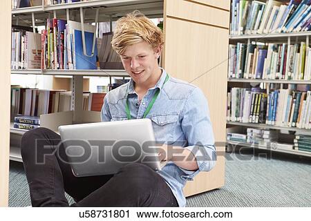 Stock Image - Male College Student Studying In Library With Laptop. Fotosearch