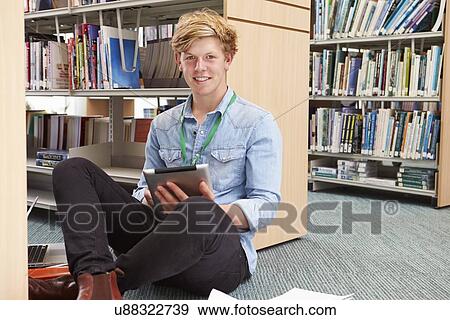 Stock Photo - Male College Student Studying In Library With Digital Tablet. Fotosearch