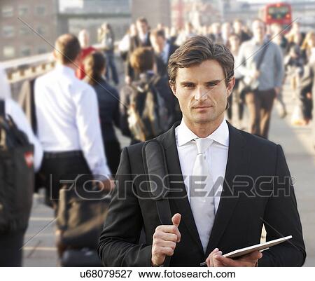 Stock Photo - Male commuter in crowd carrying tablet. Fotosearch