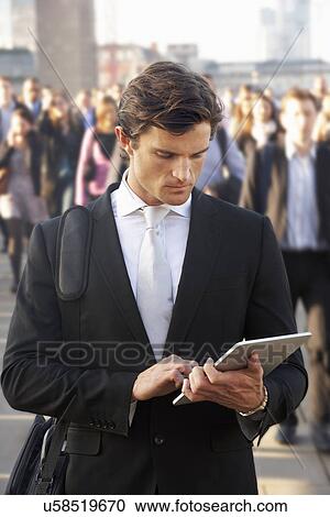 Stock Image - Male commuter in crowd using tablet. Fotosearch