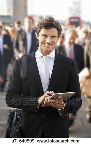 Stock Photo - Male commuter in crowd using tablet. Fotosearch
