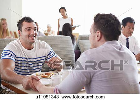 Stock Image - Male Couple Enjoying Breakfast In Hotel Restaurant. Fotosearch