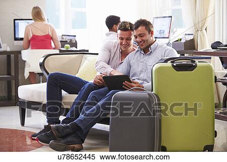 Male Couple Sitting In Hotel Lobby Looking At Digital Tablet View Large Photo Image Stock Photography - Male Couple Sitting In Hotel Lobby Looking At Digital Tablet. Fotosearch