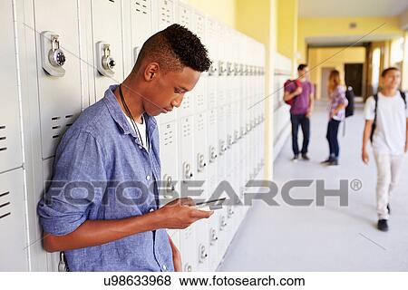 Stock Photo - Male High School Student By Lockers Using Mobile Phone. Fotosearch