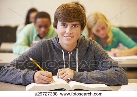 Stock Photo - Male High School Student Studying At Desk In Classroom. Fotosearch