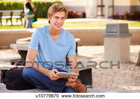 Stock Image - Male High School Student Using Digital Tablet Outdoors. Fotosearch