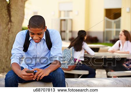 Stock Image - Male High School Student Using Phone On School Campus . Fotosearch