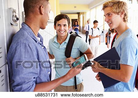Stock Image - Male High School Students By Lockers Looking At Mobile Phone. Fotosearch