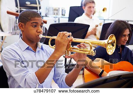 Stock Photo - Male Pupil Playing Trumpet In High School Orchestra. Fotosearch