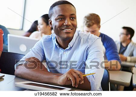 Stock Image - Male University Student Using Digital Tablet In Classroom. Fotosearch
