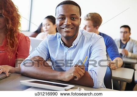 Stock Image - Male University Student Using Digital Tablet In Classroom. Fotosearch