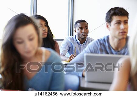 Stock Photograph - Male University Student Using Laptop In Classroom. Fotosearch