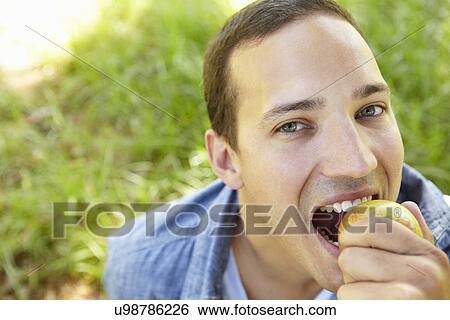 Stock Photograph - Man eating apple outdoors. Fotosearch