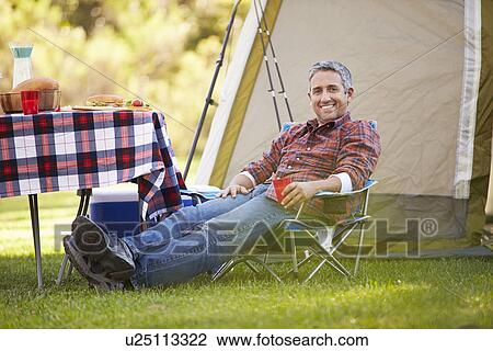 Stock Image - Man Enjoying Camping Holiday In Countryside. Fotosearch