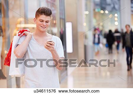 Stock Photograph - Man In Shopping Mall Using Mobile Phone. Fotosearch
