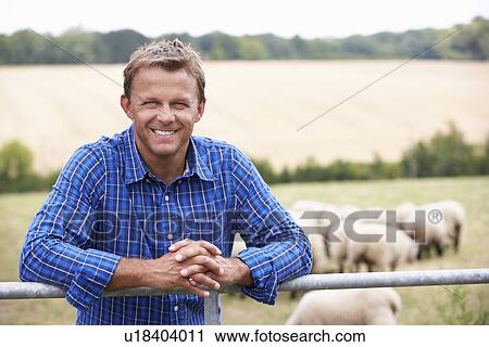 Stock Image - Man leaning on country fence. Fotosearch