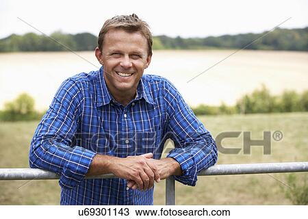 Stock Image - Man leaning on country fence. Fotosearch