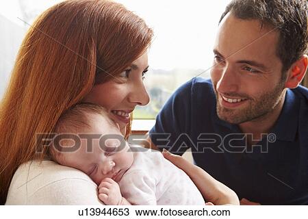 Stock Image - Man Looking At Paperwork And Playing With Pet Dog At Home. Fotosearch
