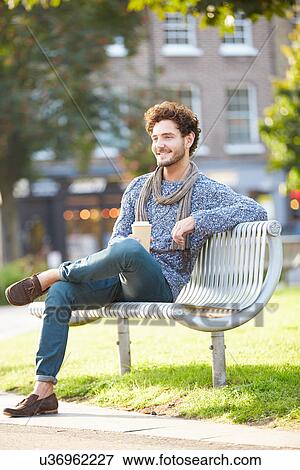 Stock Photo - Man Relaxing On Park Bench With Takeaway Coffee. Fotosearch