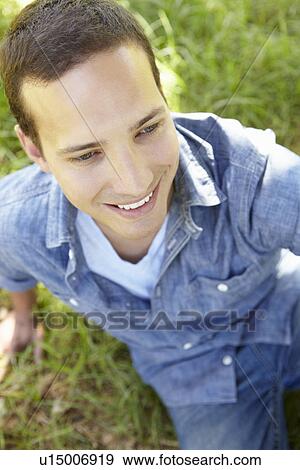Stock Photo - Man sitting on grass. Fotosearch