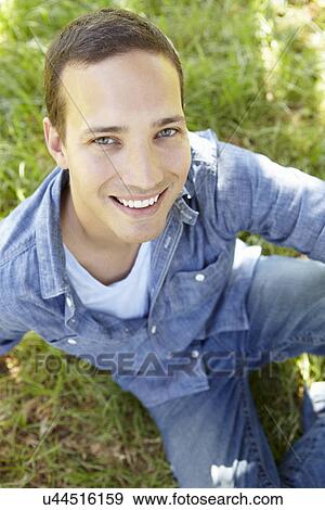 Man sitting on grass View Large Photo Image Stock Photo - Man sitting on grass. Fotosearch