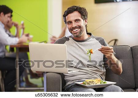 Man Sitting On Sofa And Eating Lunch In Design Studio View Large Photo Image Stock Image - Man Sitting On Sofa And Eating Lunch In Design Studio . Fotosearch