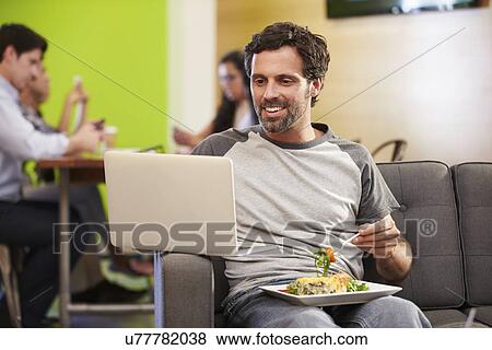 Man Sitting On Sofa And Eating Lunch In Design Studio View Large Photo Image Stock Photo - Man Sitting On Sofa And Eating Lunch In Design Studio . Fotosearch