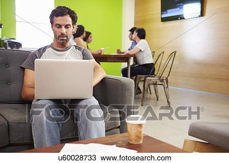 Man Sitting On Sofa And Working In Design Studio View Large Photo Image Stock Image - Man Sitting On Sofa And Working In Design Studio . Fotosearch